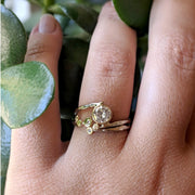 Organic Moissanite Ring set that is one of a kind, pictured with matching band on hand amongst greenery.
