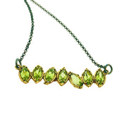 Close up shot of pendant on Peridot Two Tone Cherin Necklace. This pendant has seven marquise shaped peridot gems all set in yellow gold. The peridot gems are all mostly vertical, some alternating to a slight diagonal to make a more interesting and organic pendant.