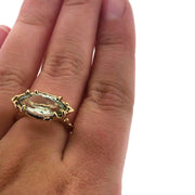 Full view of Marquise Prasiolite Organic Ring on womans hand to help give an idea of its scale. This ring has a marquise shaped prasiolite set horizontally in a gold band and setting. The band and setting has an organic look with little bumps and divets throughout it.