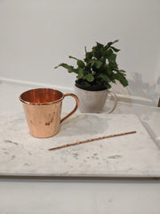 Full view of copper cocktail stirrer next to copper mug.