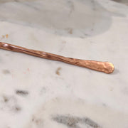 Detail shot of hammered textured tip of copper cocktail stirrer.